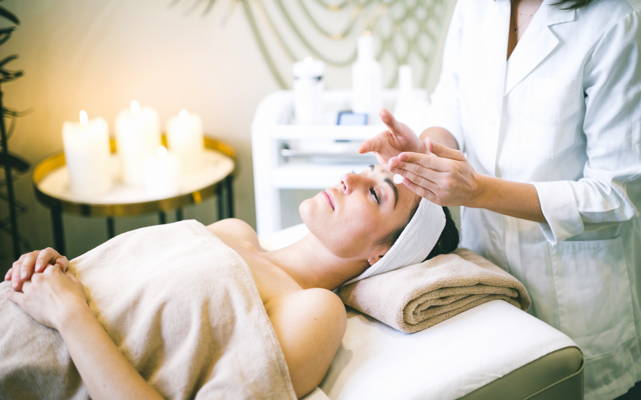 Client relaxing on a treatment bed by candlelight during the Trifusion Skin Ritual